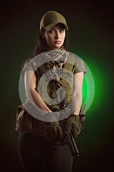The girl in military special clothes posing with a gun in his hands on a dark background in the haze