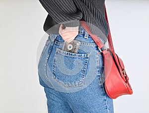 A girl in a mimes fit jeans, a sweater and with a red bag on the edge pulls out a retro audio cassette from her pocket