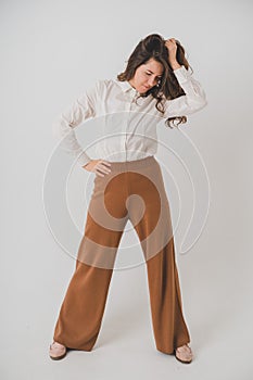 Girl in minimalist and comfortable clothes on a white background. She grabbed her hair and looked down.