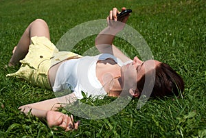 Girl with a mobile phone laying on a grass