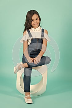 Girl model in jeans overall sit on chair