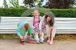 Girl with mom and brother wearing roller skates in the Park on t