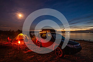 Girl and mom sitting at bonfire in tourist camping  in the evening