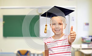 Girl in mortarboard showing thumbs up at school