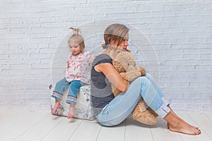 A girl, mother and child on the background of a white brick wall