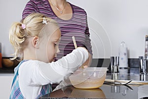 Girl and mother cooking together in kitchen