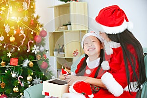 Girl and mother in santa claus costume sitting and unbox the present on sofa .Happy New year and merry Christmas with