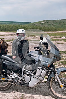 Girl motorcyclist in a helmet. Dressed in a jacket with a turtle, body armor, knee pads. Traveling is an extreme hobby. Safety and