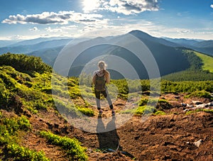 Girl on mountain peak with green grass at sunset in summer