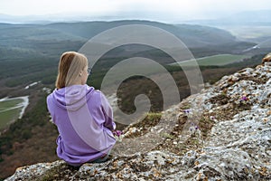 Girl on mountain peak looking at beautiful mountain valley in fog at sunset in summer. Landscape with sporty young woman