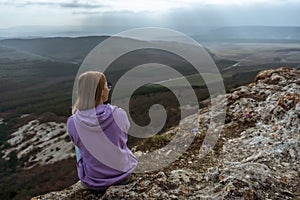 Girl on mountain peak looking at beautiful mountain valley in fog at sunset in summer. Landscape with sporty young woman