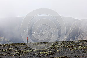 Girl on a mountain slope in the background of rocks in fog