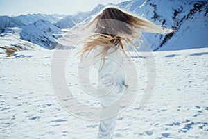 Girl in the mountains in winter. Beautiful winter nature. Snowy mountain peaks.