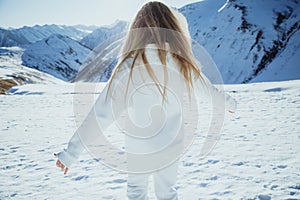 Girl in the mountains in winter. Beautiful winter nature. Snowy mountain peaks.