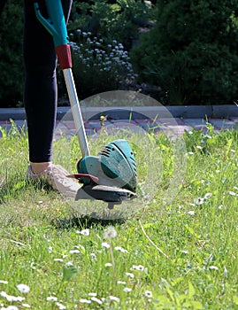 Girl mows grass with trimmer