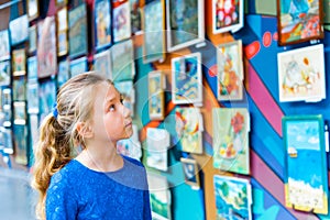 A girl in a museum at an exhibition of paintings studies fine art, examining paintings by famous authors of painters