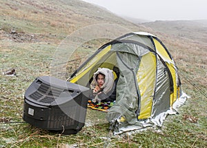 The girl on the nature lies in a tent and watches the old TV