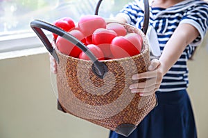 Girl in navy blue striped dress handing basket of red hearts represents helping hands, family support, morale, purity, innocence,