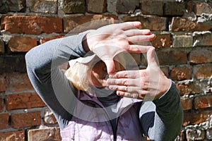 A girl near a brick wall with her hands imagines a camera. St. Veronica& x27;s Day Photographer& x27;s Day .