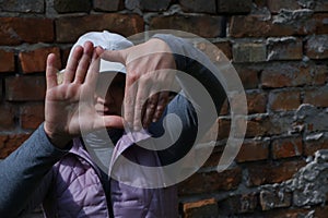 A girl near a brick wall with her hands imagines a camera. St. Veronica's Day Photographer's Day .