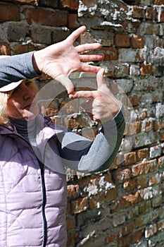 A girl near a brick wall with her hands imagines a camera. St. Veronica's Day Photographer's Day .