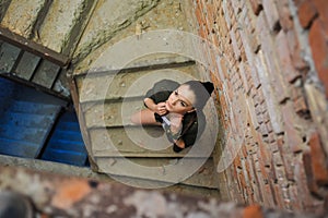 Girl near the brick wall in military style.