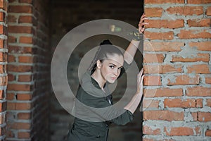 Girl near the brick wall in military style.