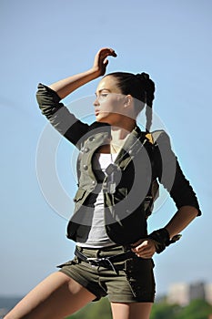 Girl near the brick wall in military style.