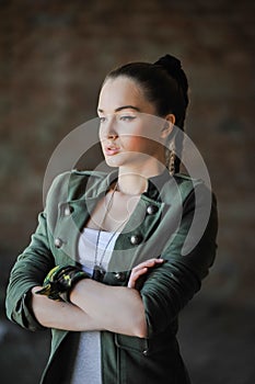 Girl near the brick wall in military style.