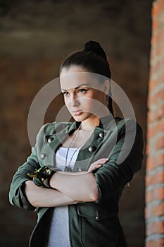 Girl near the brick wall in military style.