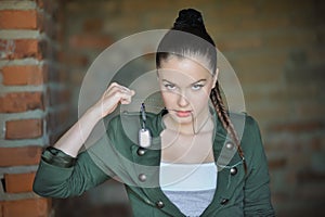 Girl near the brick wall in military style.