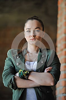 Girl near the brick wall in military style.