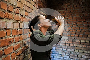 Girl near the brick wall in military style.