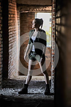 Girl near the brick wall in military style.