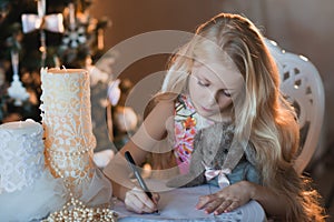 The girl near a Christmas tree with a favorite toy rabbit writes a letter to Santa, boxes, Christmas, New Year, lifestyle, holiday