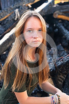 Girl near the coals from the conflagration in the background.