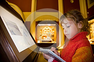 Girl near monitor writes at excursion in museum