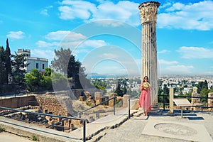 A girl near a Roman column in Carthage. Tourists at the Museum excavations of the ancient city in Tunisia