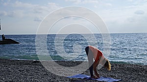 Girl near the sea doing yoga on a beach at sunrise