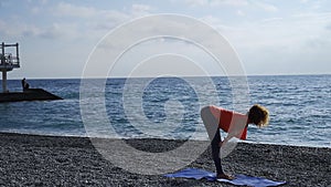 Girl near the sea doing yoga on a beach at sunrise