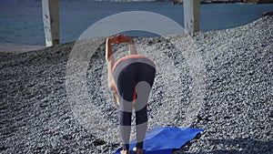 Girl near the sea doing yoga on a beach at sunrise