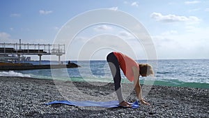 Girl near the sea doing yoga on a beach at sunrise