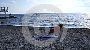 Girl near the sea doing yoga on a beach at sunrise