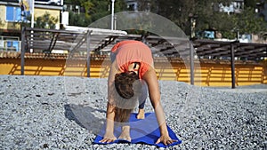 Girl near the sea doing yoga on a beach at sunrise