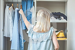 Girl near a wardrobe with clothes can not choose what to wear. Heavy Choice Concept has nothing to wear