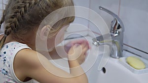 A girl near the washstand rinsing her mouth after brushing her teeth