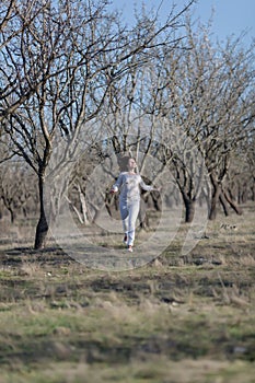 Girl in white running along old almond garden