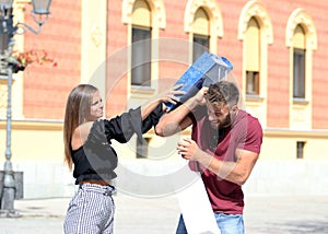 The girl nervously hits her boyfriend on the head,with a shopping bag.