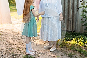 Girl next to an elderly woman. granddaughter helps her grandmother. a girl in a green dress is holding clothespins for wet clothes