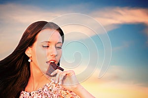 Girl nibbling the bar of chocolate